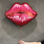 Pink lips-shaped foil balloon with a red ribbon