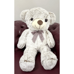 Large plush teddy bear with a plaid bow sitting on a burgundy chair