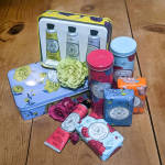 Assorted floral-themed soap and lotion gift set in colorful tins and tubes