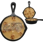 Three cast iron skillet candles with a rustic label