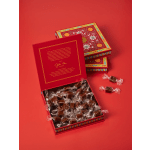 Red gift boxes filled with wrapped caramels on a red background