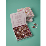 Box of individually wrapped caramels in decorative floral gift boxes on teal background
