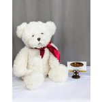 White teddy bear with a red ribbon sitting beside a florist card