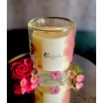 Glass candle with floral decoration beside a red rose