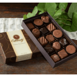 Box of assorted chocolates beside green leaves