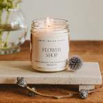 Lit candle in a glass jar labeled Flower Shop