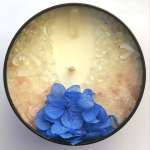 Round candle with blue flowers embedded in wax