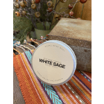 White sage soy wax candle in a round tin on a woven textile
