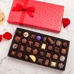 Box of assorted chocolates beside a pink gift box with a ribbon