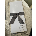 Clear acrylic gift box with a black ribbon and a card reading Eat Sleep Ski