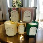 Five labeled scented candles in glass jars arranged on a table.