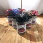 Five jars of Sanders chocolate caramels topped with decorative bows.