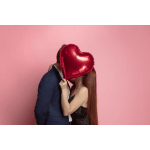 Couple posing with a red heart-shaped balloon against a pink background