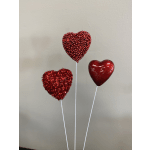 Three red heart-shaped decorative picks on white sticks