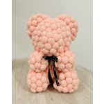 Pink teddy bear made of pom-pom-like spheres with a black ribbon bow
