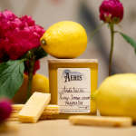 Yellow candle with lemons and pink peonies nearby