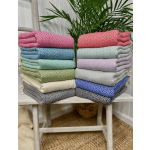 Stacks of colorful herringbone-patterned throws folded on a wooden bench