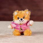 Small plush fox in a pink shirt sitting on a surface