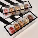 Two clear boxes of assorted macarons with black trim