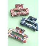 Three floral-pattern hair claw clips on a mint background
