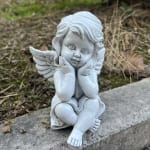 Small white angel figurine sitting on a stone ledge