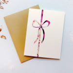 Two greeting cards, one tied with a pink ribbon bow