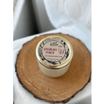 A scented candle in a glass jar with a gold lid on a wood slice
