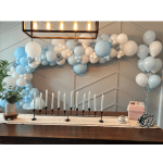 Blue and white balloon garland above a table with candles