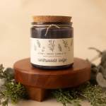 Dark candle jar with cork lid on a wooden stand
