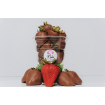 Chocolate-covered strawberries in a clear plastic cup with one strawberry in front