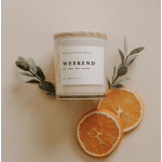 Scented candle in a glass jar with orange slices and faux greenery