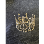 Jeweled crown with gold and silver filigree on a dark fabric surface