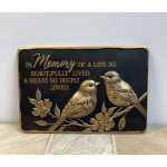 Memorial plaque with two birds and gold lettering on a black background