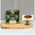 Box of mint chocolates beside a flower shop card on a wooden slab