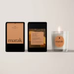 Three packaged candles, one lit in a glass holder