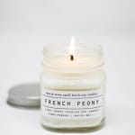 Lit scented candle in a glass jar with a white label