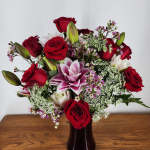 Bouquet of red roses and pink lilies in a dark vase