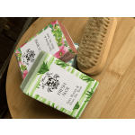 Two floral soap bars and a wooden scrub brush on a table.