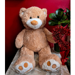 Plush teddy bear beside a potted plant wrapped with red tinsel