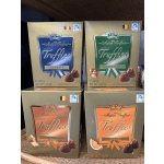 Four boxes of assorted chocolate truffles stacked on a shelf.