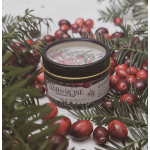 A jar candle surrounded by cranberries and evergreen sprigs