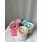Five flower-shaped candles in colored glass holders on a table