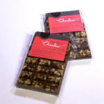 Two packaged dark chocolate bars with red labels on a white surface