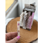 Hand holding a small lip balm tube in front of a display box