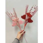 Two glittery heart sprays, one pink and one red, held in a hand
