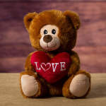 Brown teddy bear holding a red heart with the word LOVE