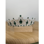 Silver tiara with green gemstones on a wooden block