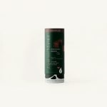 A cylindrical cocktail mixer container with dark green labeling