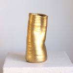 Gold metallic vase on a white pedestal