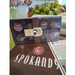 Box of assorted chocolate truffles on a counter with flower bouquets behind it